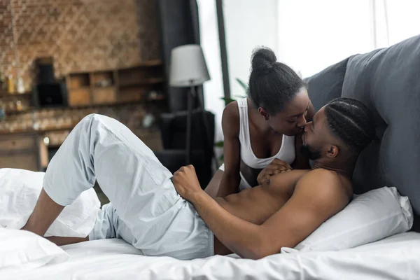 Africano americano pareja besos en dormitorio - foto de stock