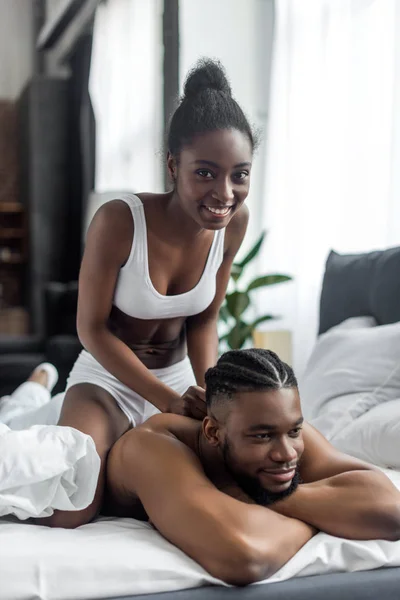 Sorrindo casal afro-americano em roupa interior olhando para a câmera na cama — Fotografia de Stock