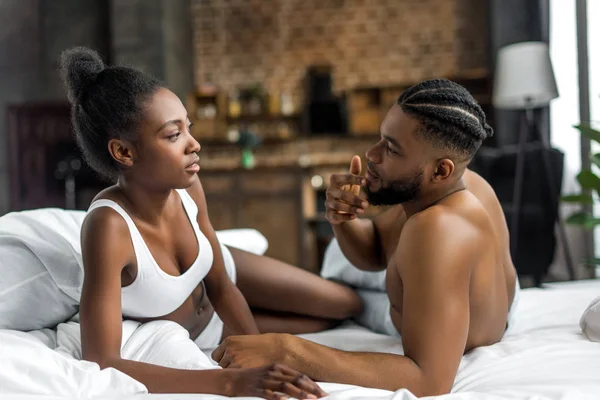 Africano casal americano olhando uns para os outros na cama no quarto — Fotografia de Stock