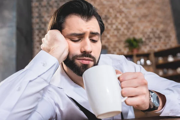 Handsome loner businessman looking into cup of coffee at kitchen — Stock Photo