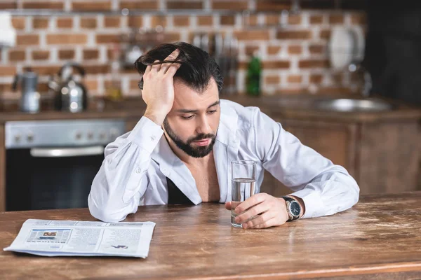 Schöner Einzelgänger Geschäftsmann, der morgens am Tisch sitzt und in der Küche ein Glas Wasser betrachtet — Stockfoto