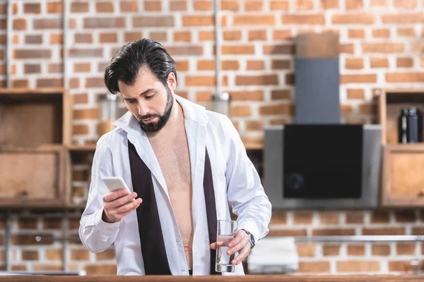 Bonito solitário empresário olhando para smartphone de manhã na cozinha — Fotografia de Stock