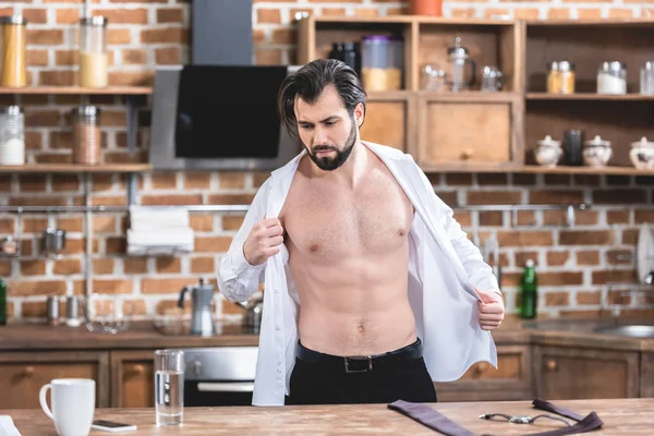 Muscoloso bello solitario uomo d'affari indossa camicia in cucina — Foto stock