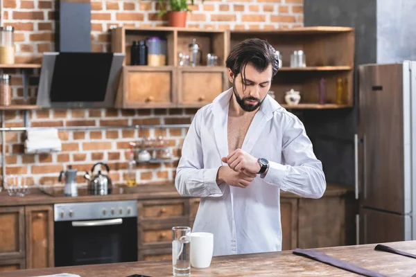 Bonito solitário empresário verificando o tempo de manhã na cozinha — Fotografia de Stock