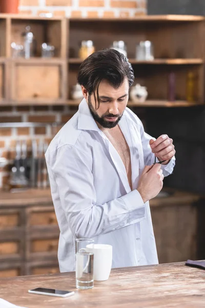 Bello solitario uomo d'affari con camicia sbottonata guardando giù in cucina — Foto stock