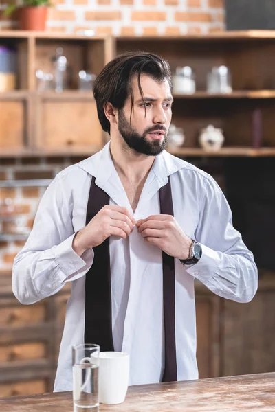 Portrait of handsome loner businessman buttoning shirt at kitchen — Stock Photo