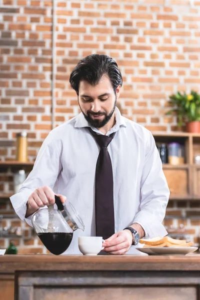 Bonito solitário empresário derramando café em xícara na cozinha — Fotografia de Stock