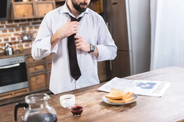 Imagem cortada de empresário solitário que fixa gravata na cozinha — Fotografia de Stock