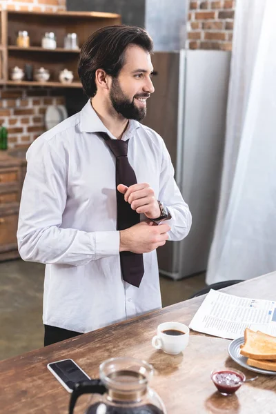 Lächeln gutaussehender Einzelgänger Geschäftsmann knöpft Ärmel in der Küche — Stockfoto