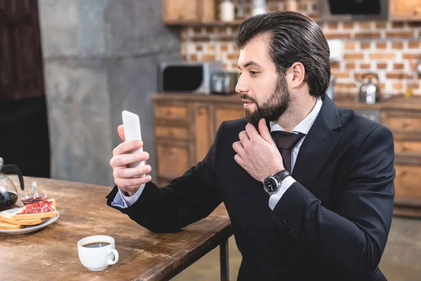 Вид збоку красивого бізнесмена, який бере селфі зі смартфоном на кухні — стокове фото