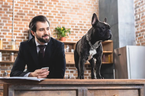 Cheerful handsome loner businessman looking at dog at kitchen — Stock Photo