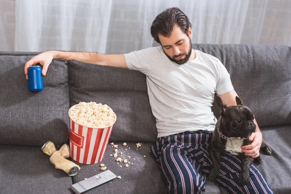 Bonito solitário sentado com buldogue no sofá e segurando bebida na sala de estar — Fotografia de Stock