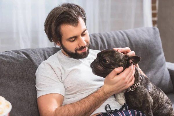 Handsome loner palming dog in living room — Stock Photo