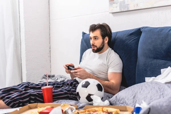 Männlicher Einzelgänger spielt Videospiel im Schlafzimmer — Stockfoto