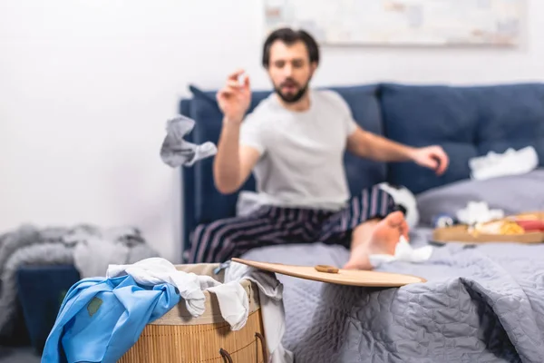 Loner throwing dirty sock into basket with laundry in bedroom — Stock Photo