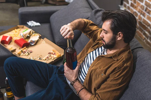 Side view of loner opening bottle of alcohol drink at living room — Stock Photo