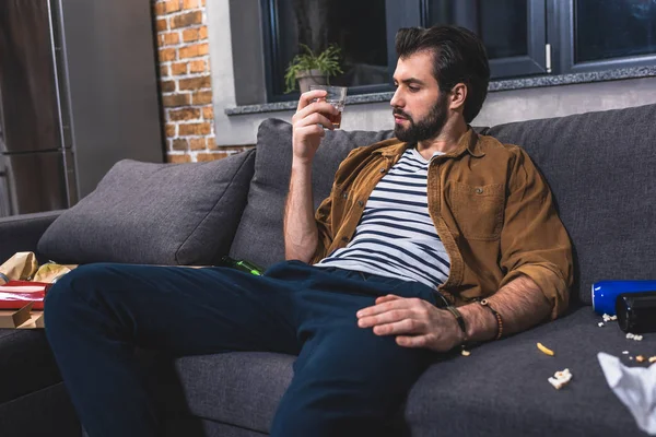 Einzelgänger blickt auf Glas Whisky im Wohnzimmer — Stockfoto