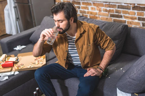Handsome loner drinking water and having hangover at living room — Stock Photo