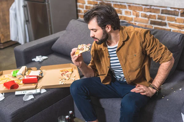 Schöner Einzelgänger, der im Wohnzimmer Pizza isst — Stockfoto