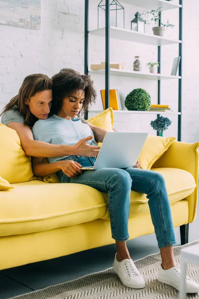 Attractive african american woman with laptop and boyfriend pointing by hand on screen — Stock Photo