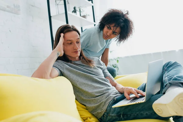 Wütende junge Afroamerikanerin schaut Freund mit Laptop an — Stockfoto