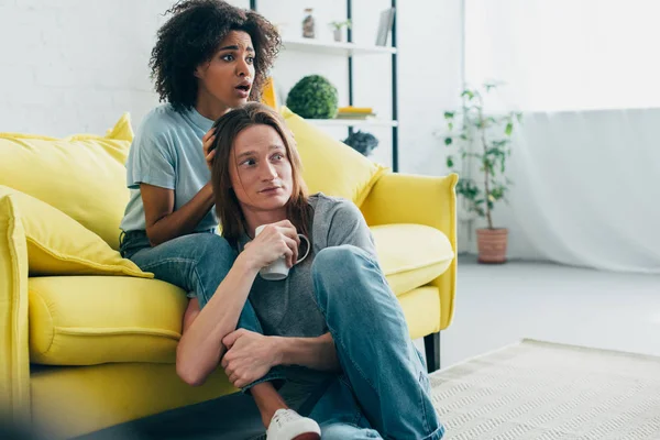 Scared multiethnic couple watching tv at home — Stock Photo