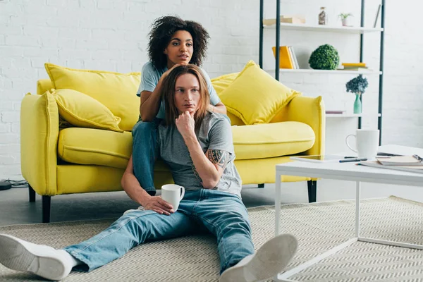 Interracial jeune couple regarder la télévision à la maison — Photo de stock