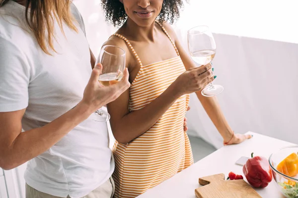Tiro recortado de casal com copos de vinho branco em pé à mesa com pimentas — Fotografia de Stock