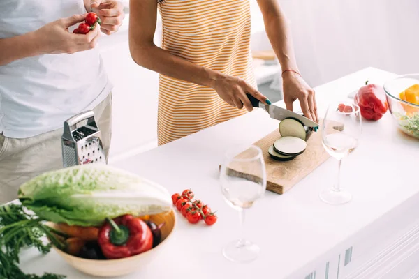 Plan recadré de femme coupant aubergine et petit ami debout près de tomates cerises à la cuisine — Photo de stock