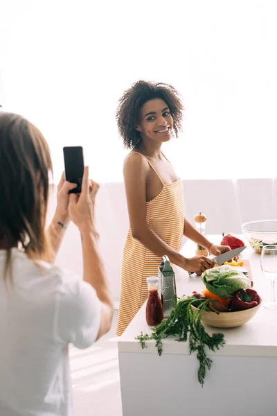 Cropped shot of man shooting african american girlfriend on smartphone — Stock Photo
