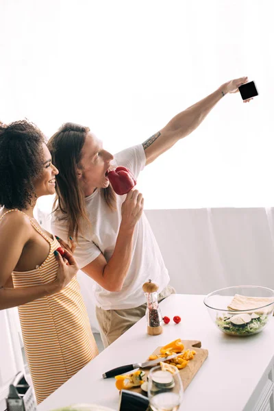 Mann hält Paprika in der Hand und macht Selfie mit Freundin mit Kirschtomaten — Stockfoto