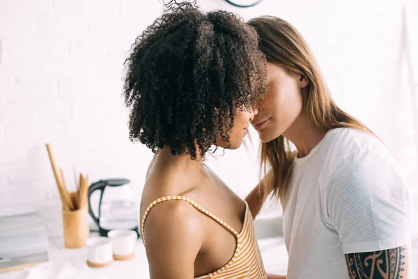 African american woman kissing boyfriend with tattooed hand — Stock Photo