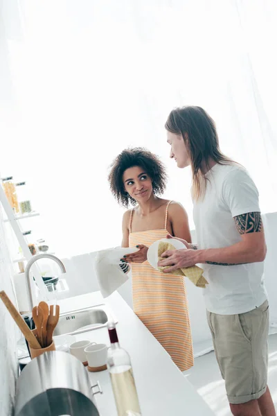 Interracial young couple washing dishes at kitchen — Stock Photo