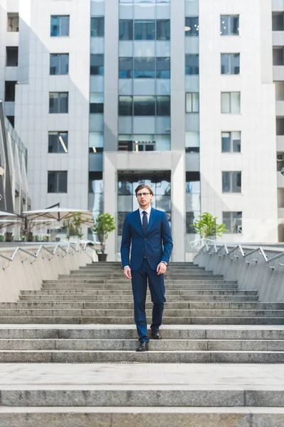 Stylish young businessman walking down stairs in business district — Stock Photo