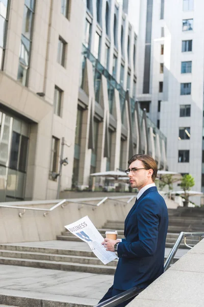 Réfléchi jeune homme d'affaires avec journal et tasse de papier de café — Photo de stock