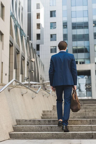 Rear view of businessman with leather briefcase going up stairs — Stock Photo