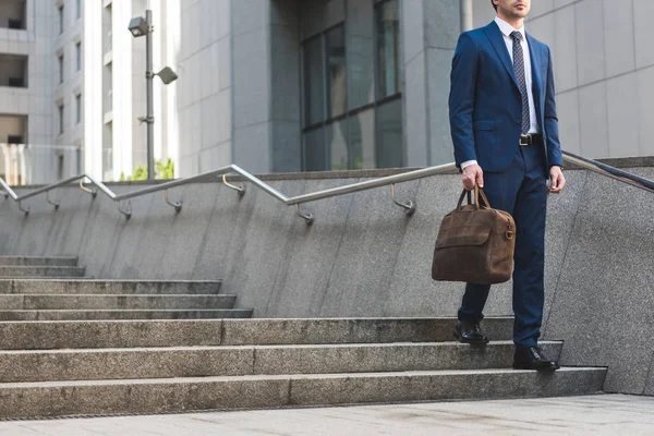 Обрізаний знімок бізнесмена в стильному костюмі з портфелем, що йде по сходах — стокове фото