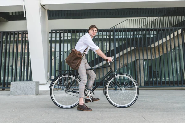 Side view of attractive young man riding vintage bicycle on city street — Stock Photo