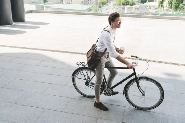 Hochwinkelaufnahme eines hübschen jungen Mannes mit Pappbecher Kaffee auf einem Oldtimer-Fahrrad — Stockfoto