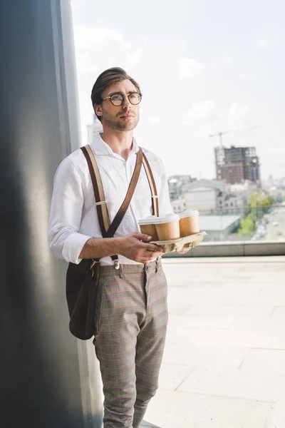 Attractive young man with paper coffee cups on cardboard tray — Stock Photo