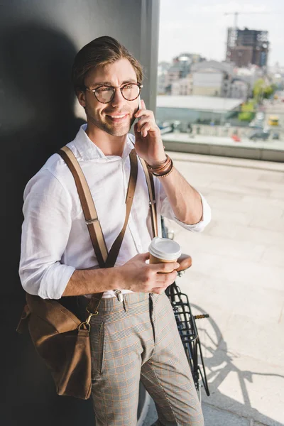 Sorrindo jovem com café para ir falar por telefone — Fotografia de Stock