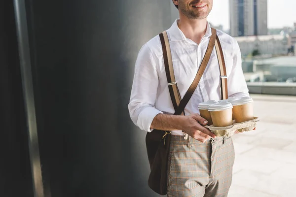 Обрезанный снимок стильного мужчины с бумажными кофейными чашками на подносе — стоковое фото