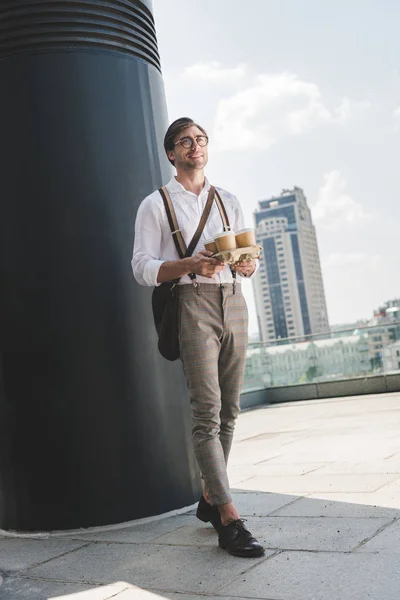 Handsome young man with paper coffee cups on cardboard tray — Stock Photo