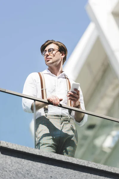 Bottom view of stylish young man using smartphone on balcony — Stock Photo