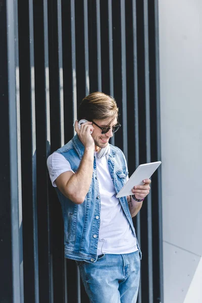 Stylish young man listening music with tablet and headphones — Stock Photo