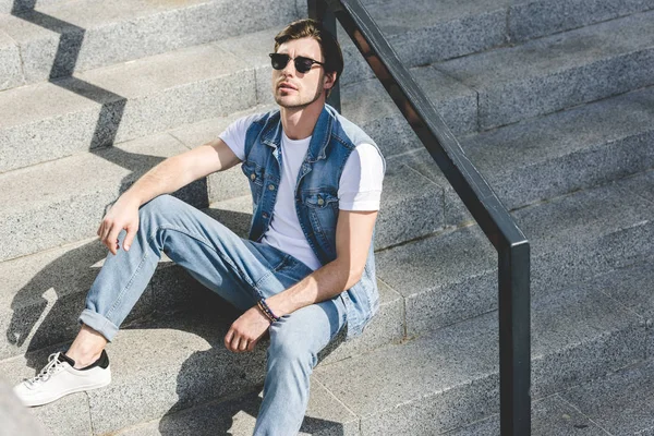 Handsome young man sitting on stairs and relaxing — Stock Photo