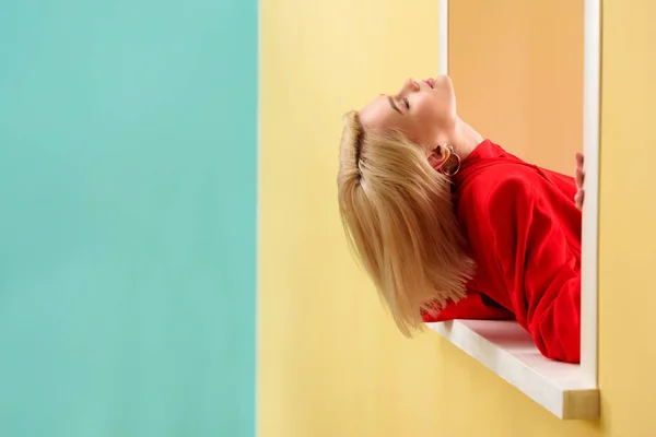 Side view of attractive blond woman in red jacket at decorative window — Stock Photo