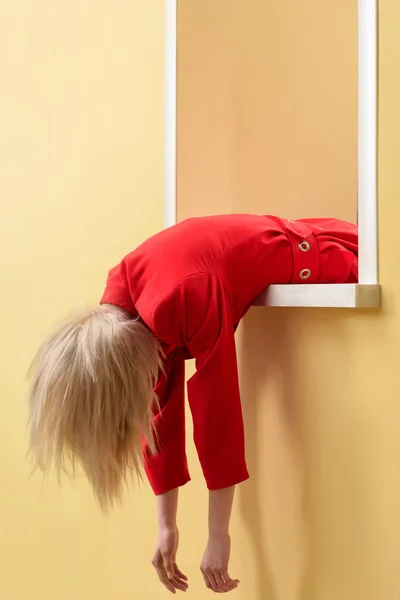 Vista parcial de la mujer en traje rojo colgando por la ventana decorativa - foto de stock