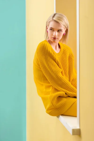 Stilvolle nachdenkliche Frau im gelben Pullover sitzt auf dekorativem Fenster — Stockfoto