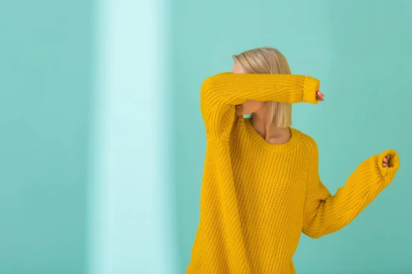 Obscured view of woman in yellow sweater posing on blue background — Stock Photo